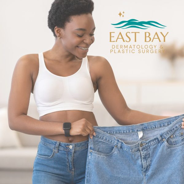 Smiling person in a white bra holds up a pair of loose jeans. Logo for East Bay Dermatology & Plastic Surgery appears in the background.